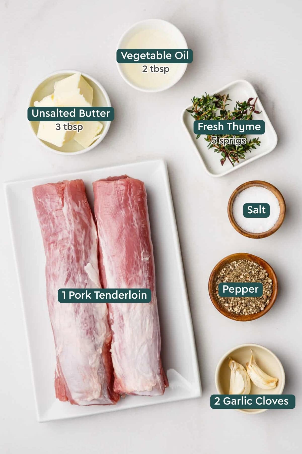 Ingredients for oven roasted pork tenderloin including oil, butter, thyme, salt, pepper, garlic, and pork.