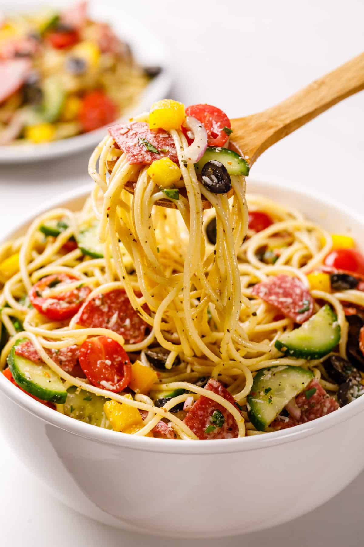 spaghetti salad served in a white bowl with a wooden spoon