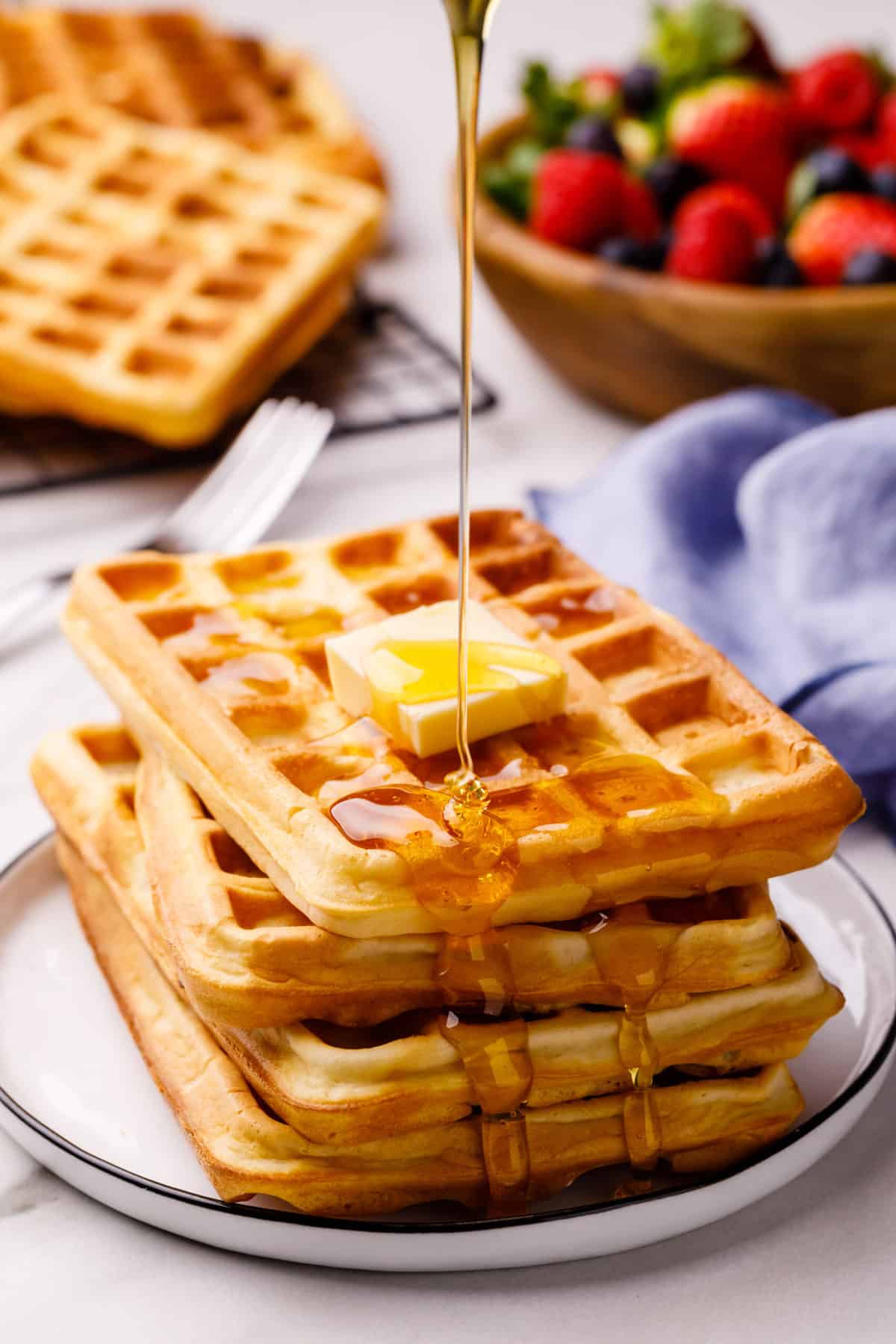 stack of four biswuick waffles topped with a slab of butter and syrup poured on top