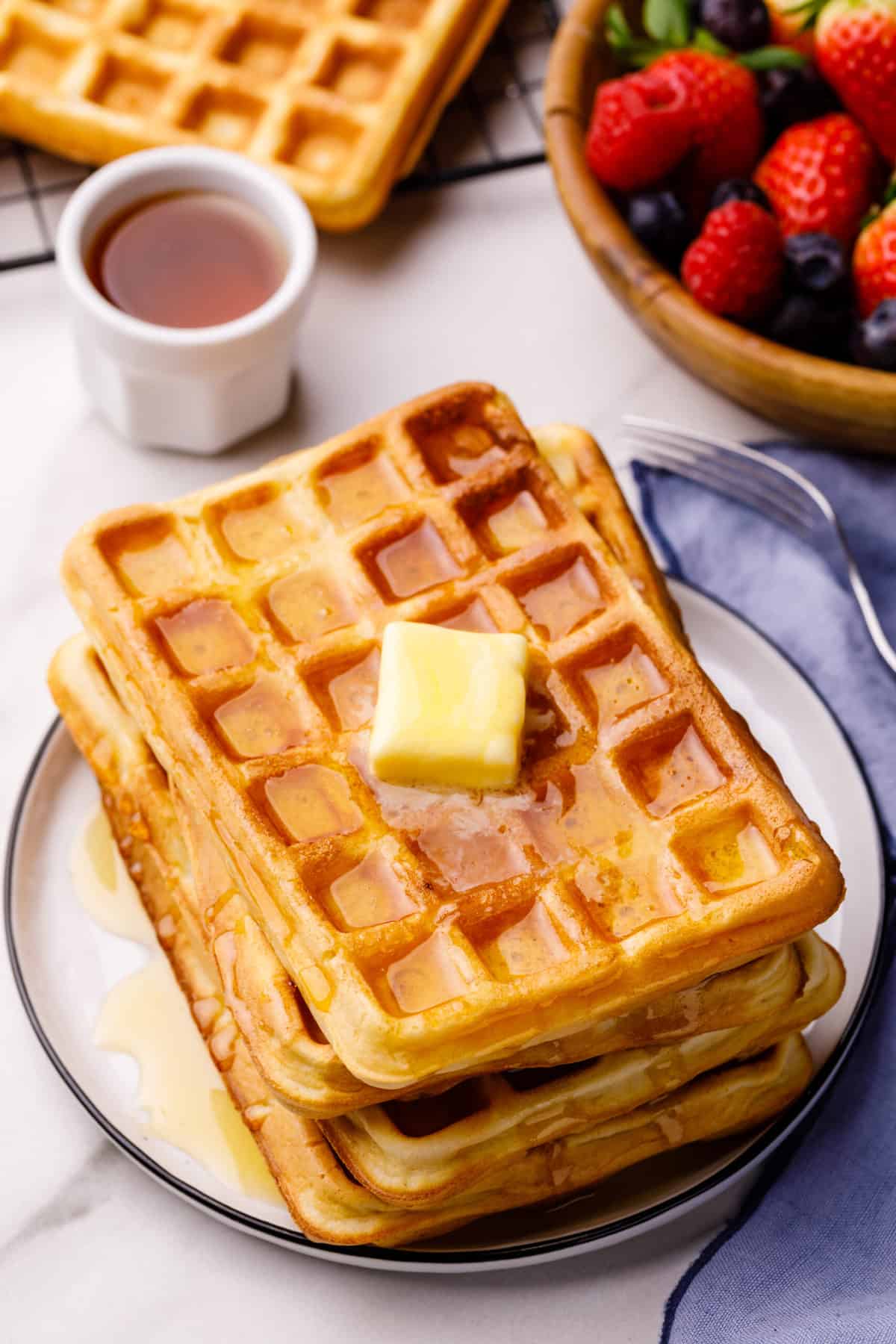 four bisquick waffles stacked on a top topped with a slab of butter and syrup