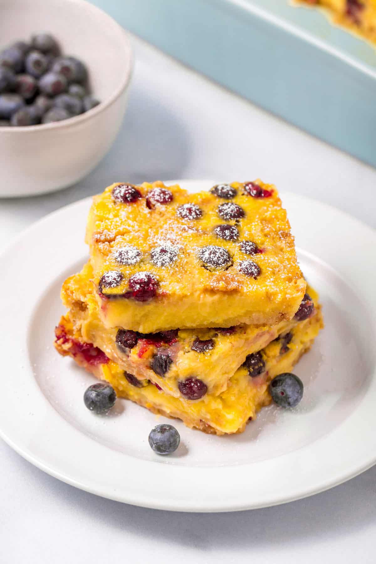 three lemon blueberry bars squares stacked on a white plate
