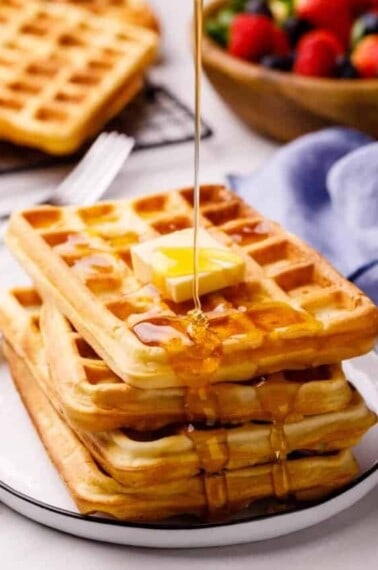 square waffles topped with butter and having syrup poured over the top