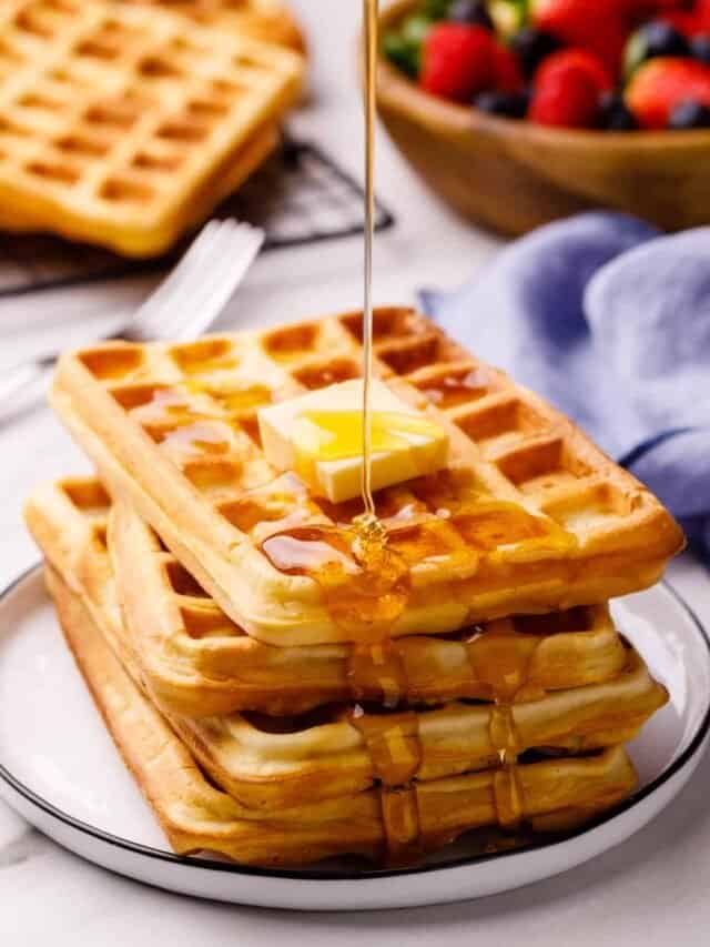 square waffles topped with butter and having syrup poured over the top 