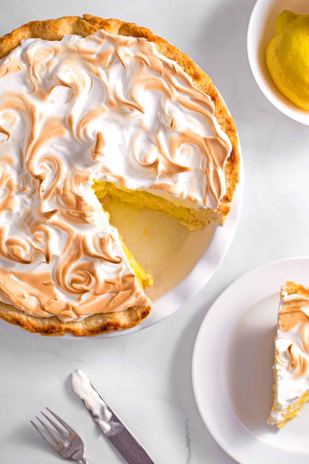 lemon meringue pie in a pie dish and a slice on a plate