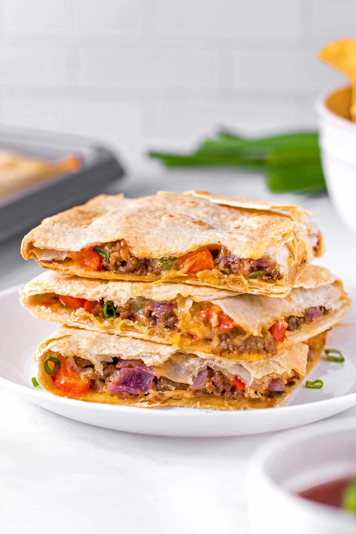 three sheet pan quesadilla squares stacked on each other served on a white plate