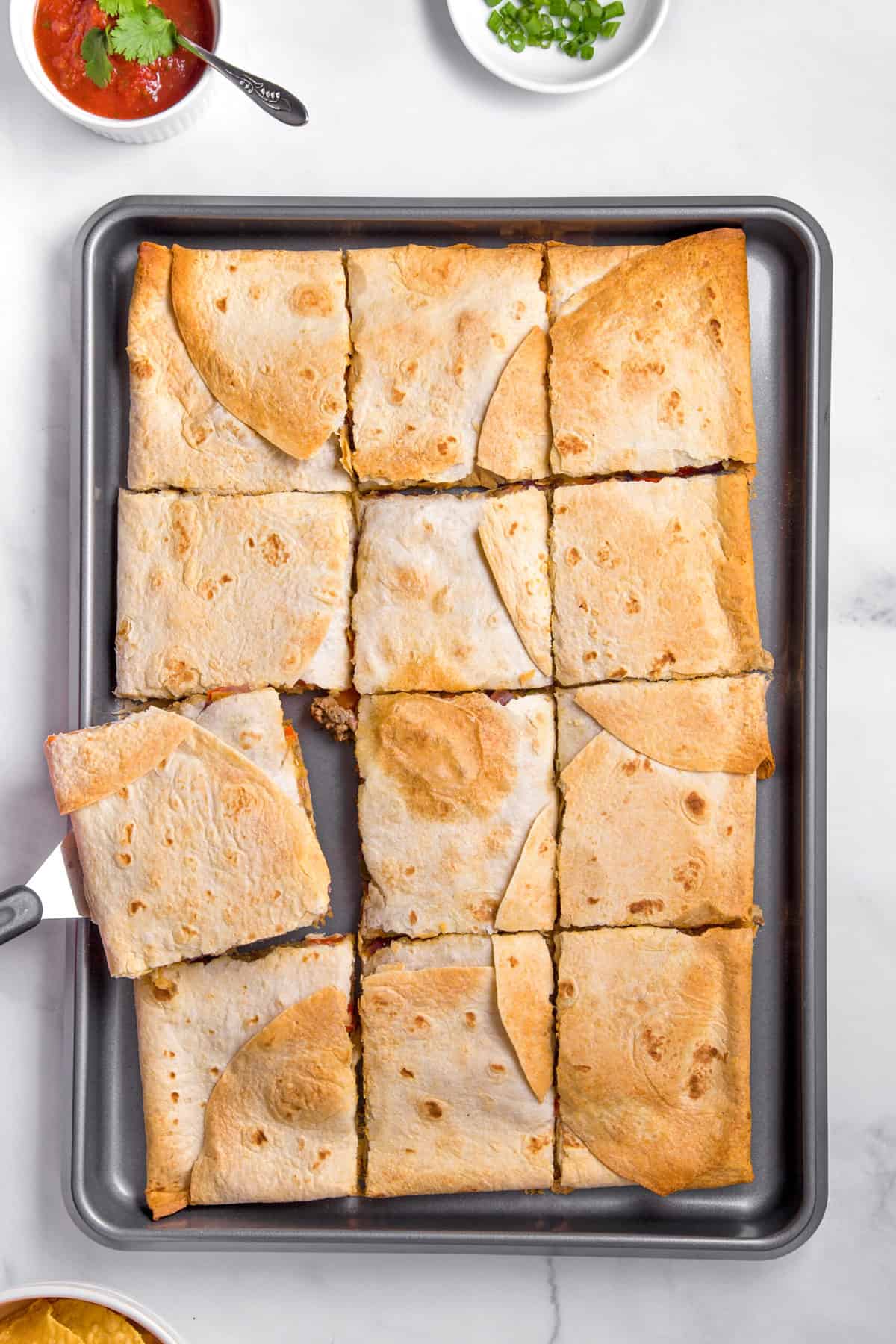 top view of baked sheet pan quesadillas cut into squares making 12 servings