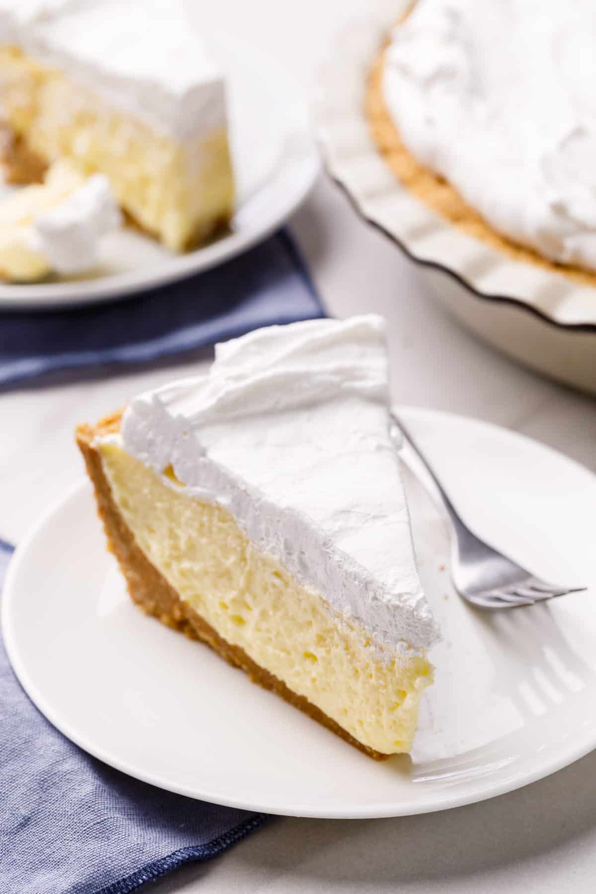 slice of banana cream pie served on a white round plate with a silver fork
