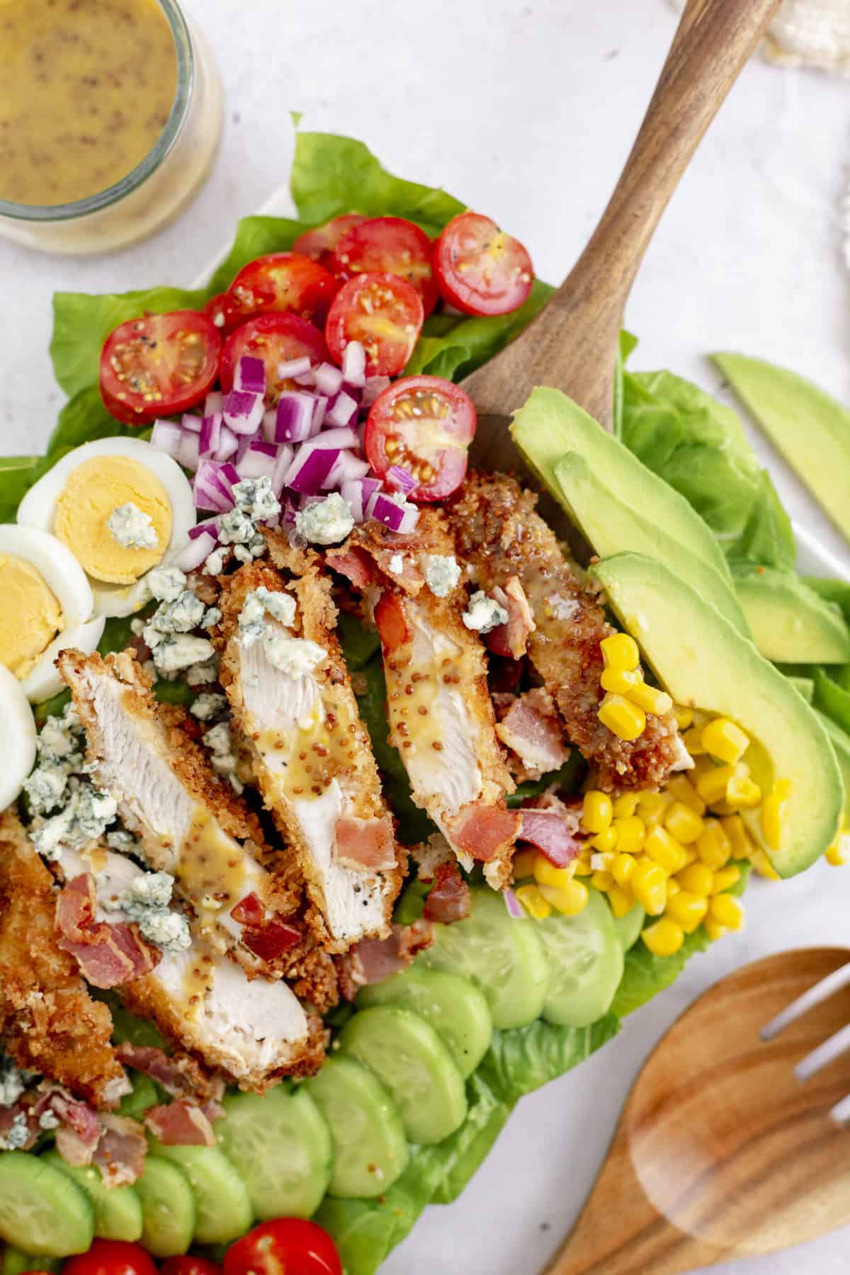 top down view of crusted chicken cobb salad with a wooden spoon