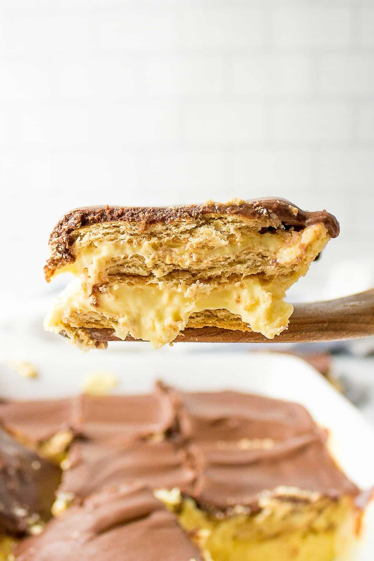 cross section of no bake chocolate eclair cake sitting on a wooden spatula