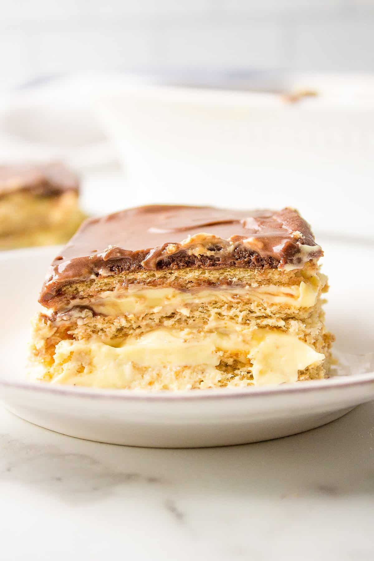 cross section image of a slice serving of no bake chocolate eclair cake served on a white plate