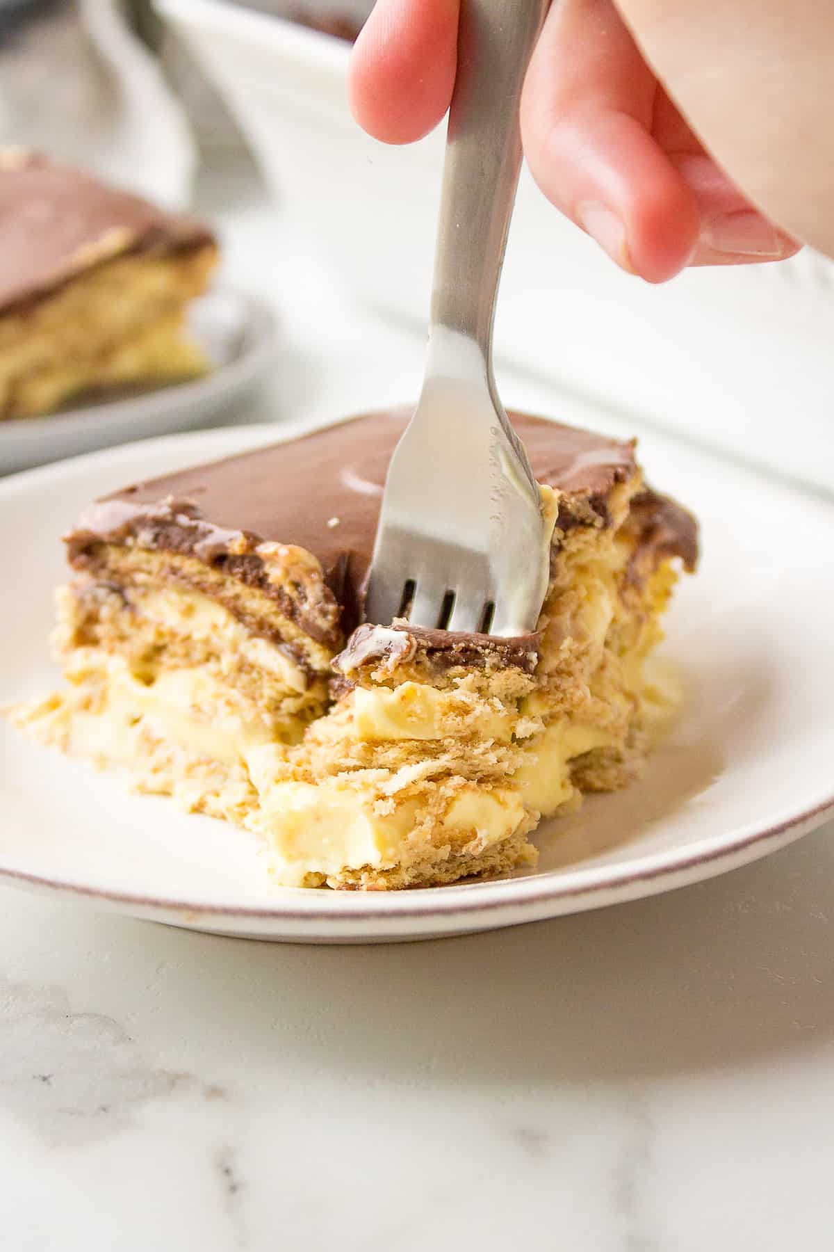 fork digging into no bake chocolate eclair cake served on a plate
