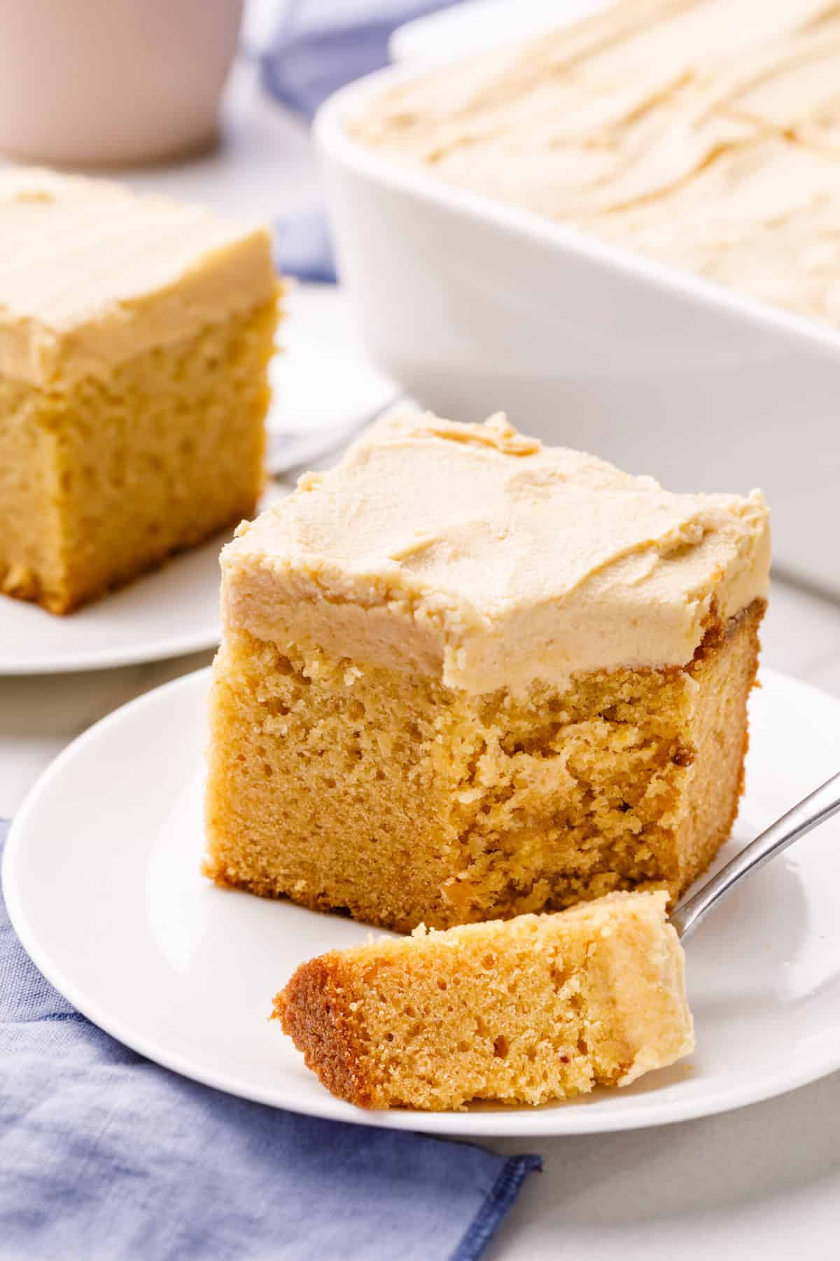 serving of peanut butter cake with peanut butter frosting served on a white round plate with a silver fork