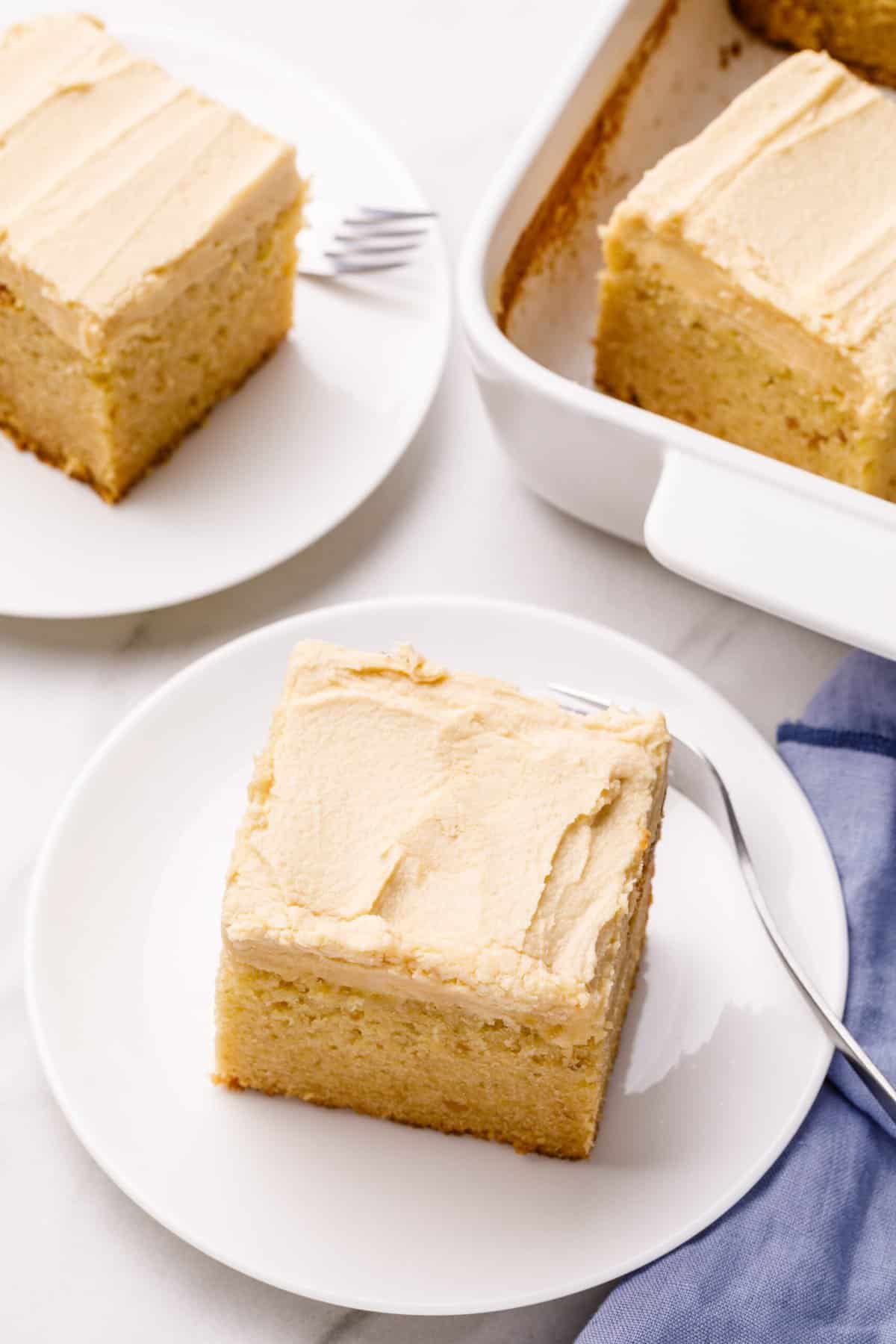 serving of peanut butter cake with peanut butter frosting served on a white round plate with a silver fork
