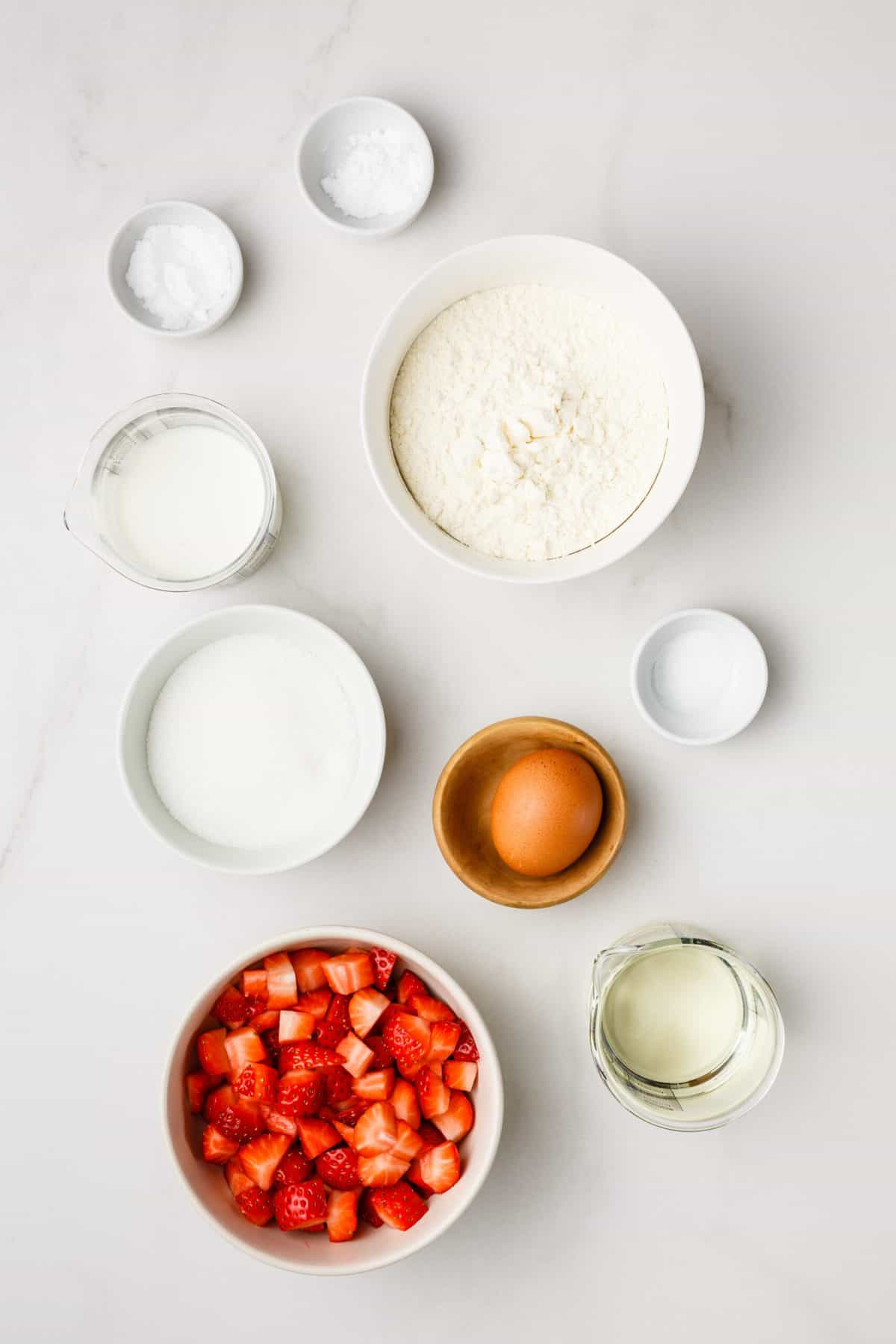 Ingredients for strawberry bread, including flour, baking powder, sugar, milk, oil, egg, berries, powdered sugar.