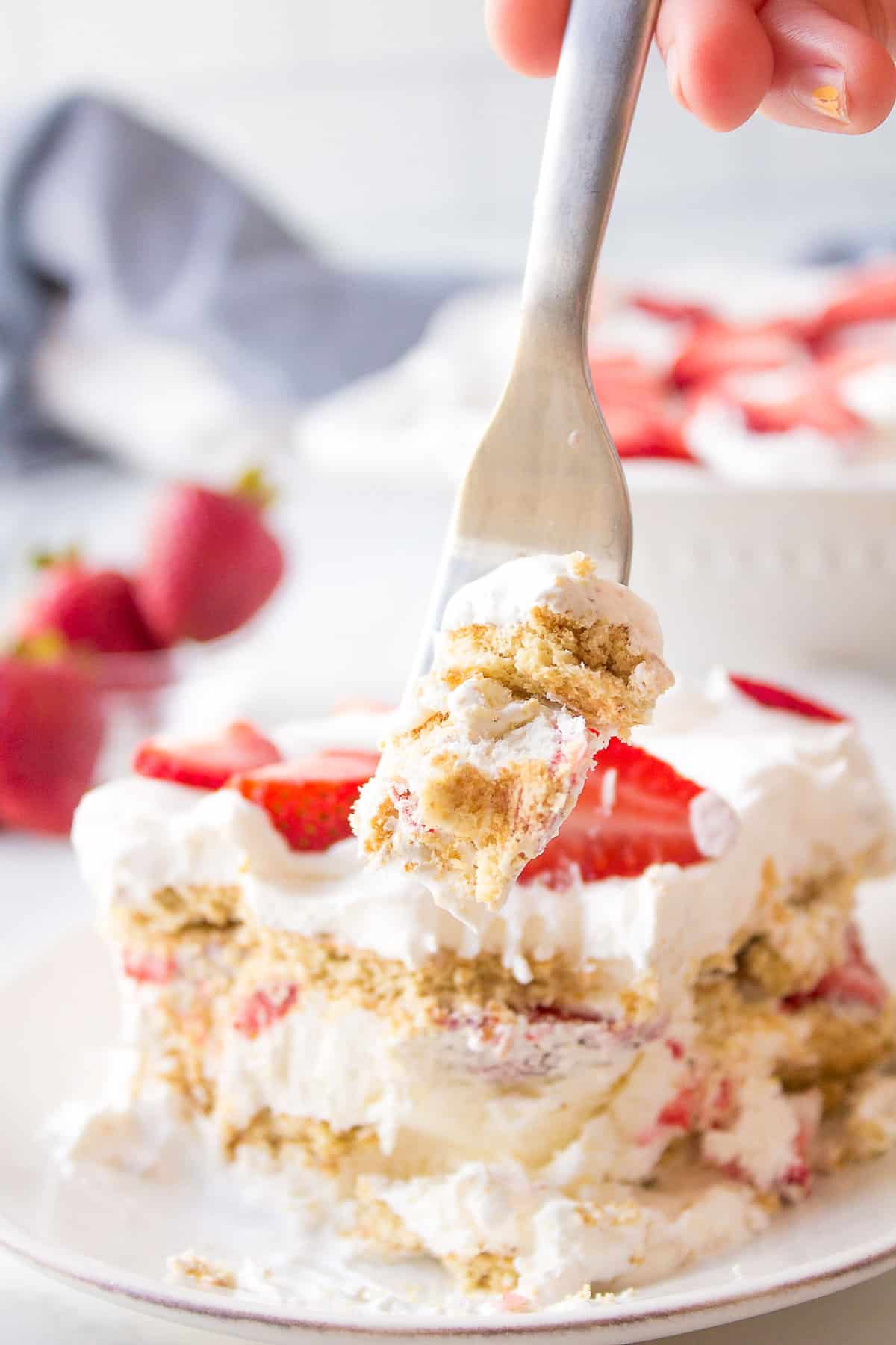 forkful of strawberry icebox cake served on a white plate