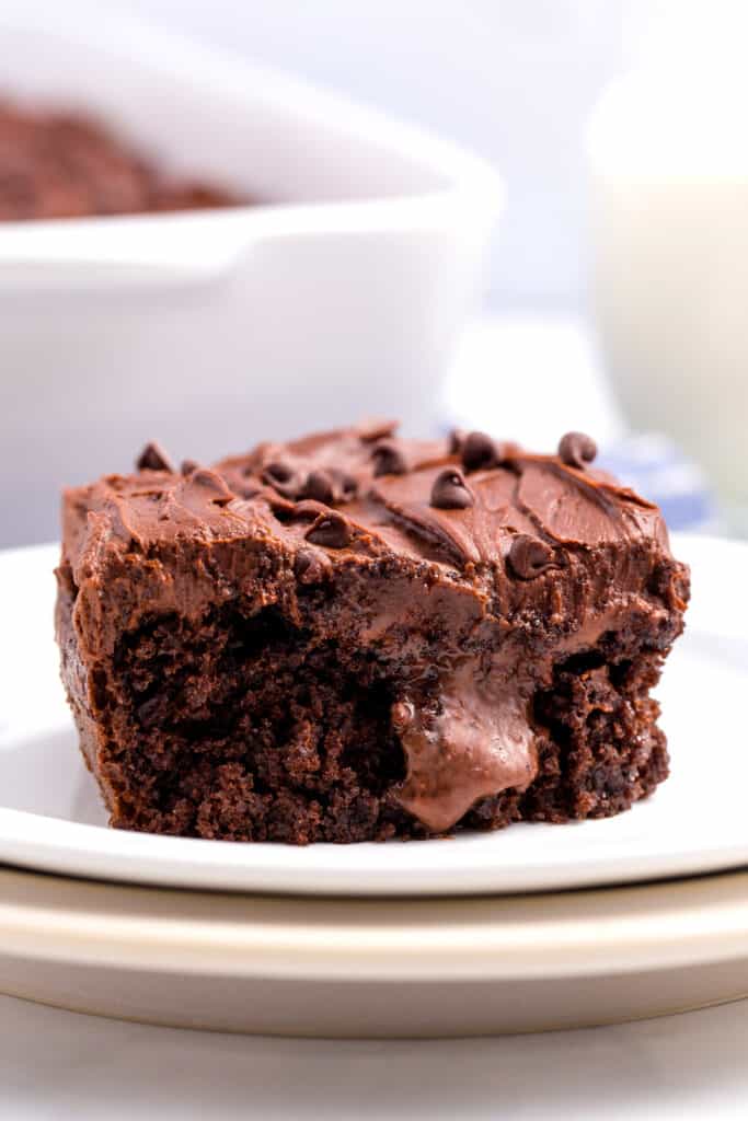 A slice of chocolate poke cake topped with chocolate chips on a plate.