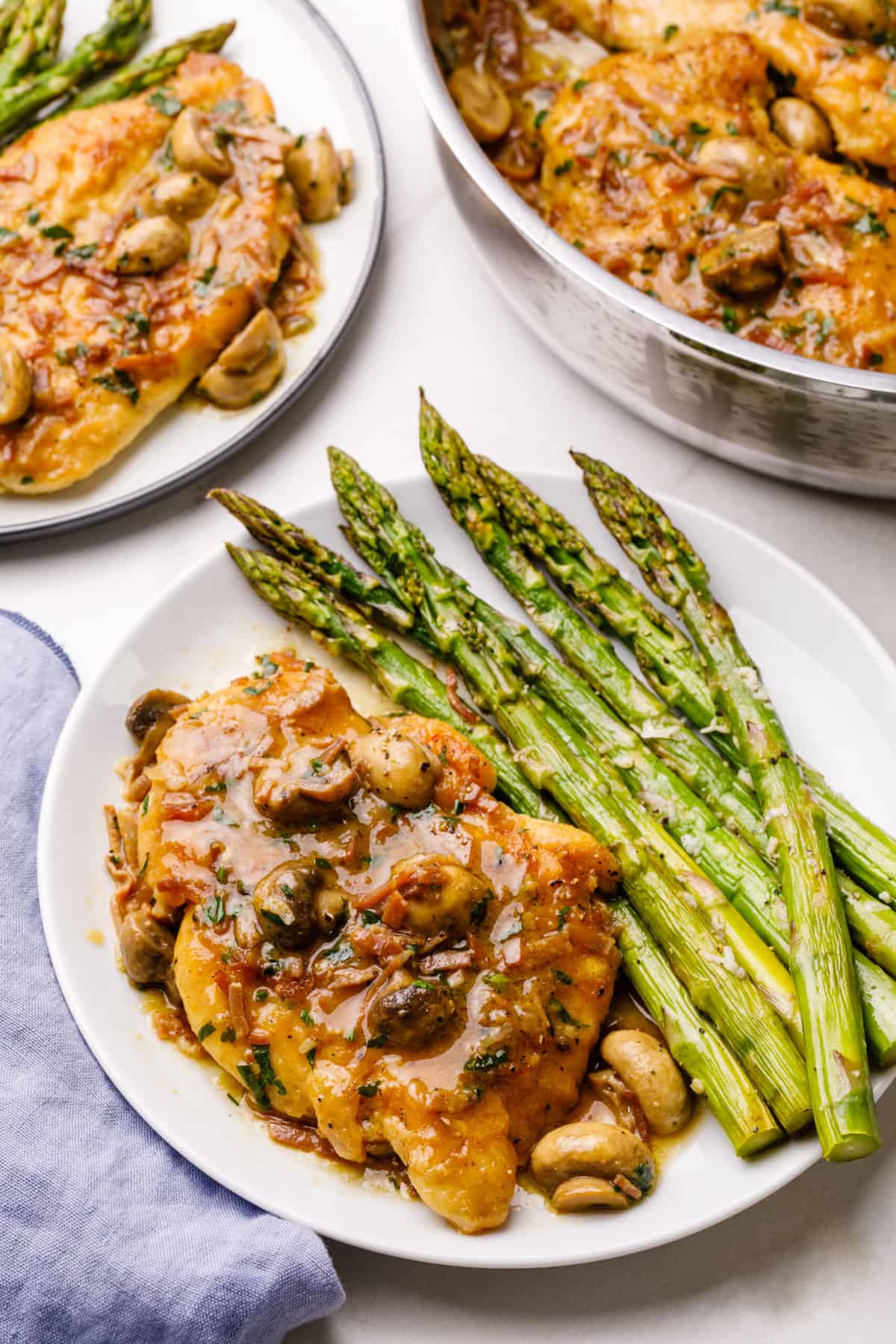 chicken marsala served on a white plate with a side of roasted asparagus