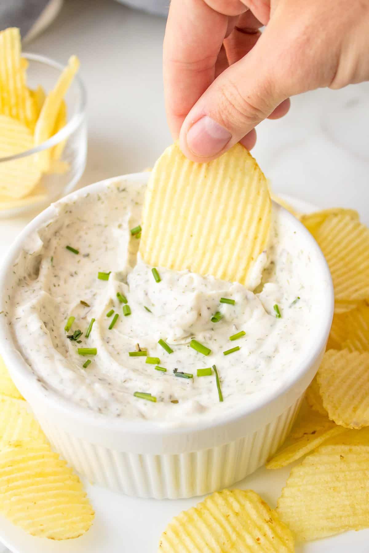chip dip served in a ceramic dish with ruffle potato chips on the side
