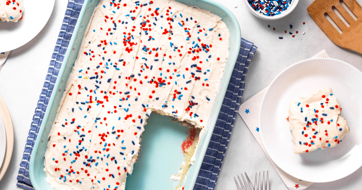 A baking dish of red, white, and blue poke cake with pieces missing and a slice on a plate.