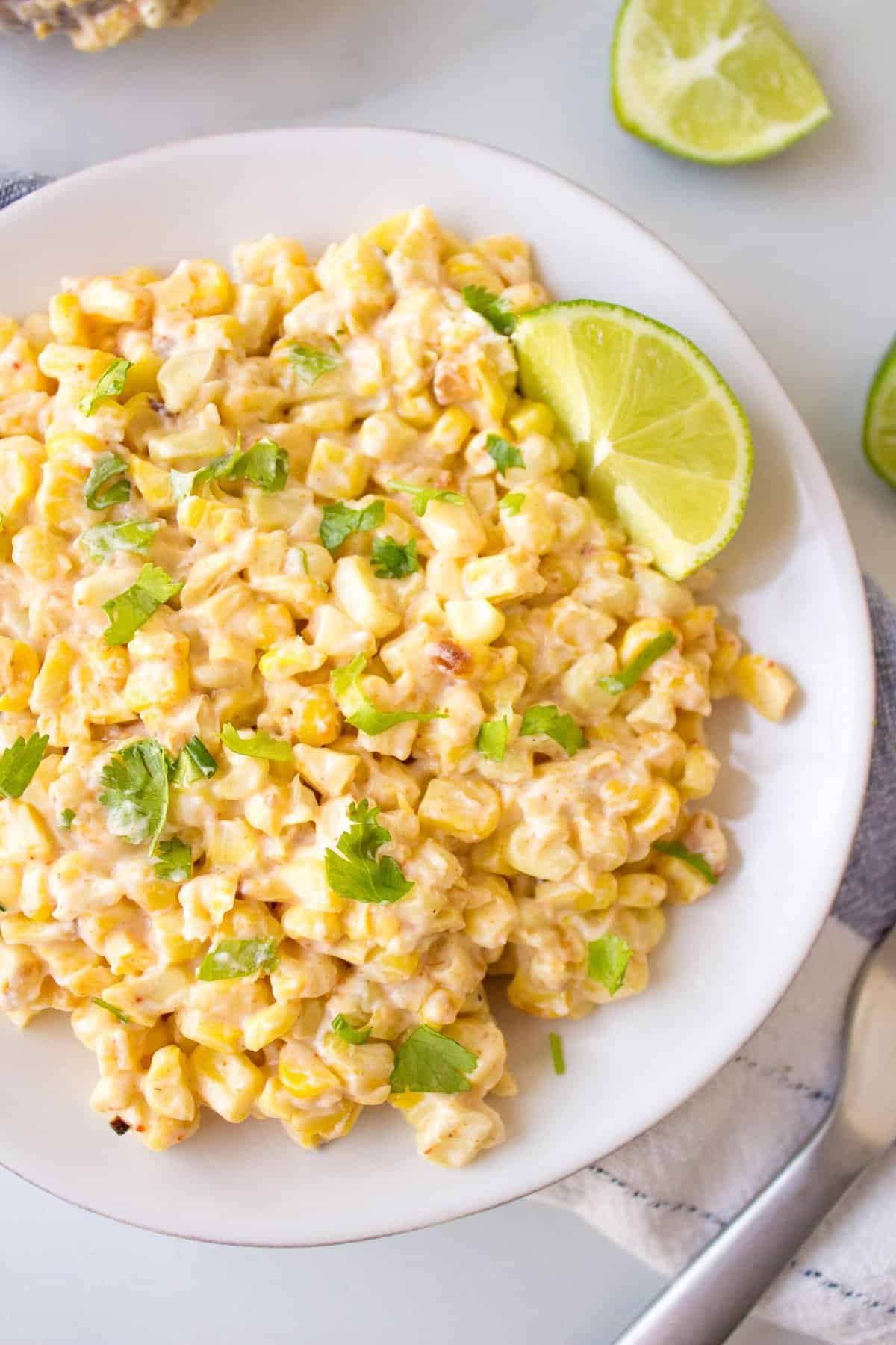 top down image of mexican corn served on a plate with a lime wedge