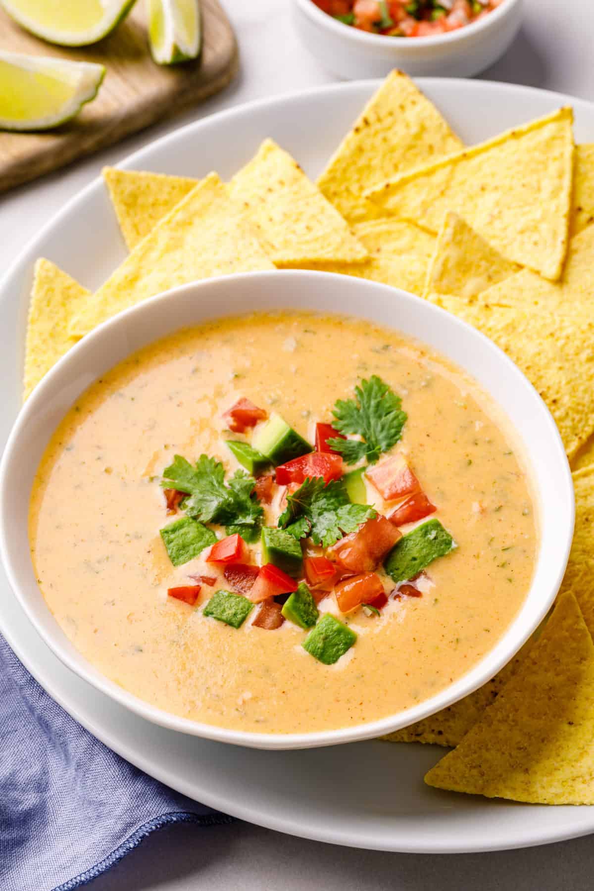 homemade queso dip served in a white bowl with a side of tortilla chips