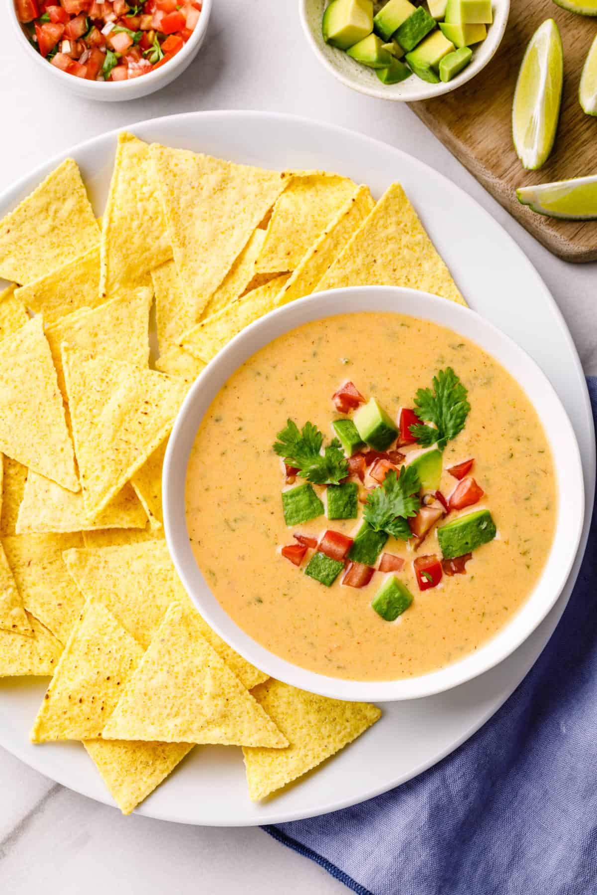 top down view of homemade queso dip served in a white bowl with a side of tortilla chips