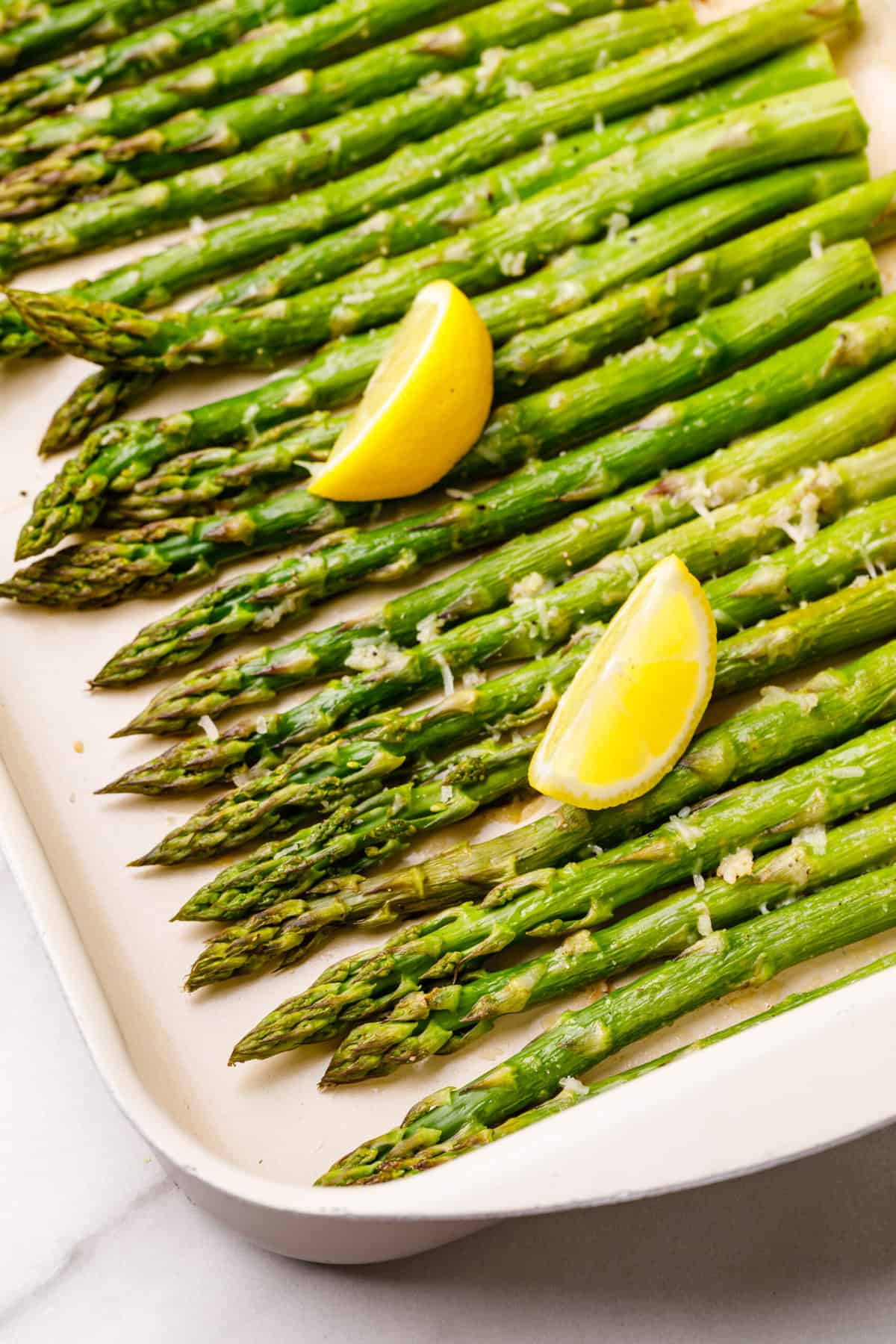 roasted asparagus on a sheet pan garnished with lemon wedges