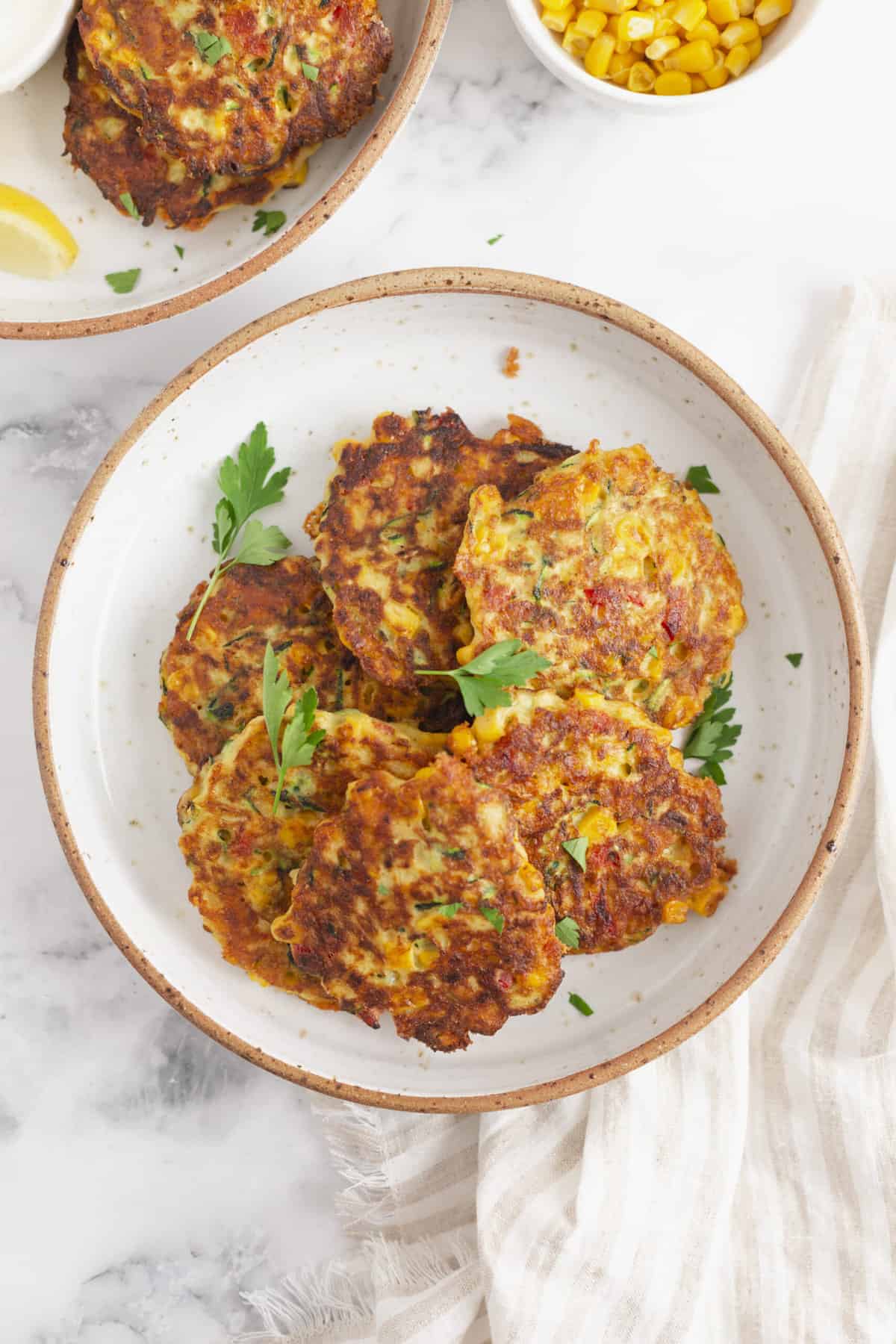 top down image of zucchini corn fritters garnished with parsley servef on a plate