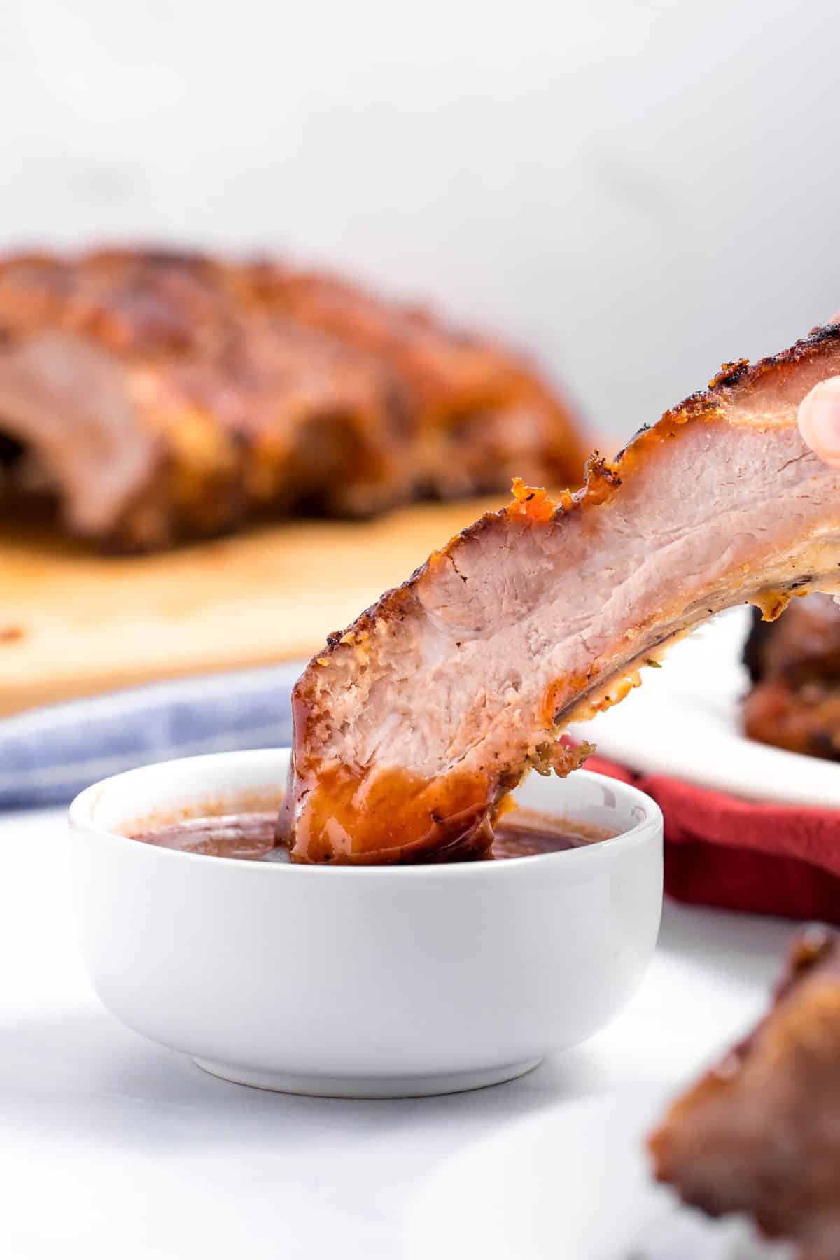 bbq rib dipped in barbecue sauce served in a white bowl 