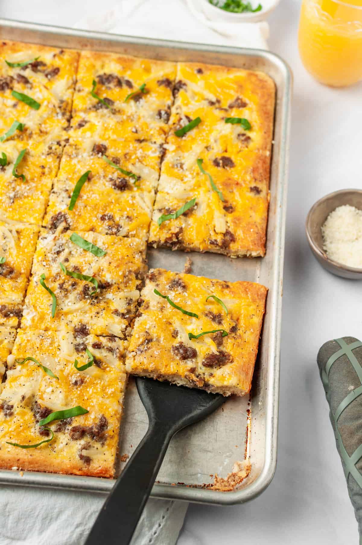 breakfast pizza served on a baking sheet, cut into squares