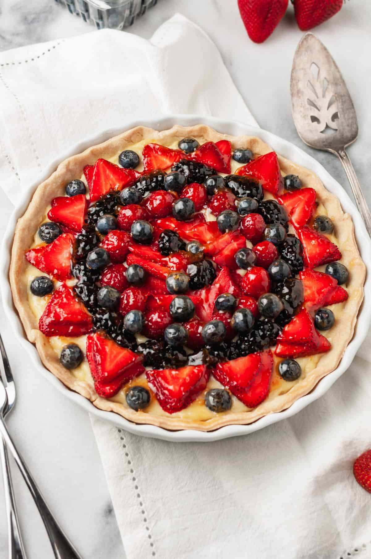 fresh fruit tart topped with fresh berries served in a pie dish