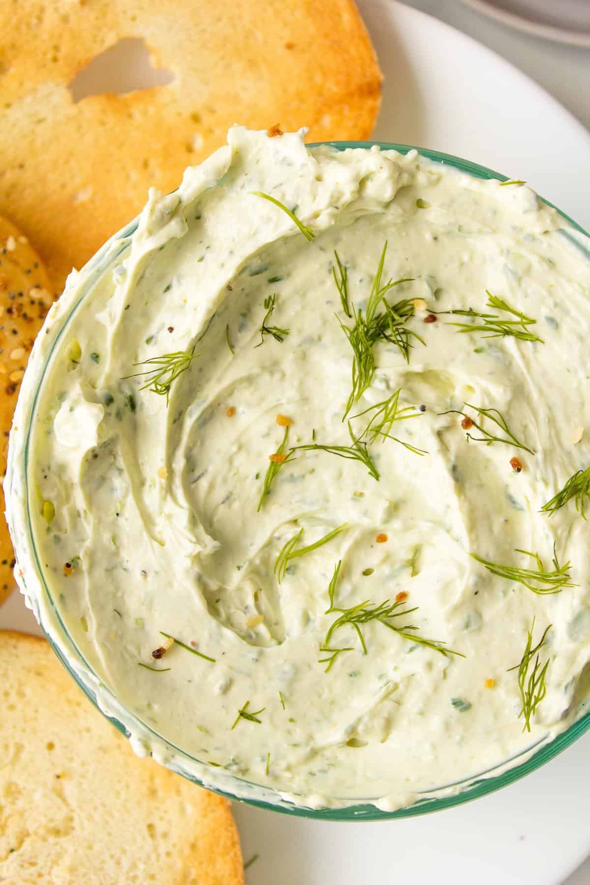 herb cream cheese dip served in a glass bowl topped with fresh dill