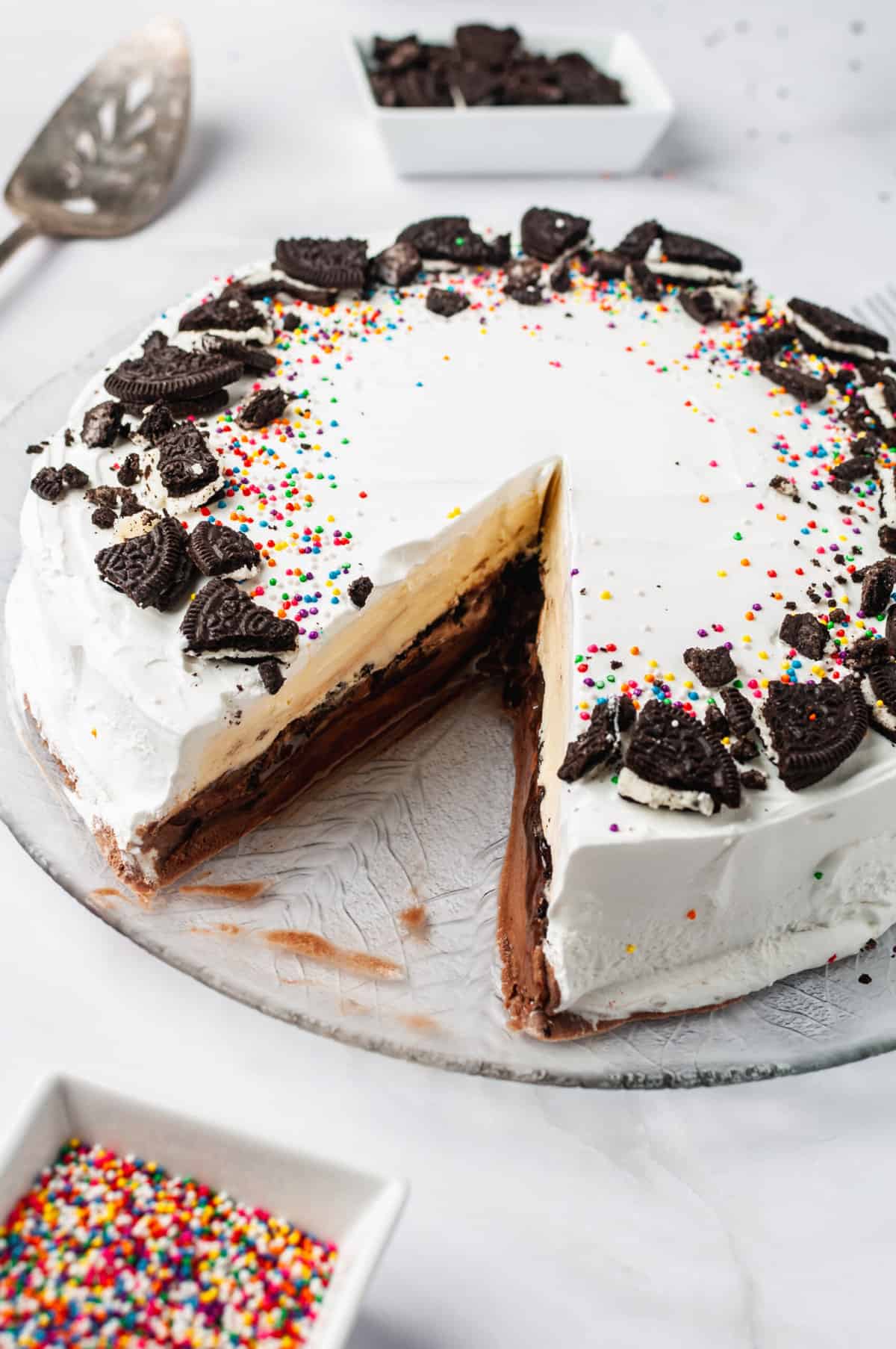 copycat dairy queen ice cream cake with a slice taken out served on a glass cake plate.