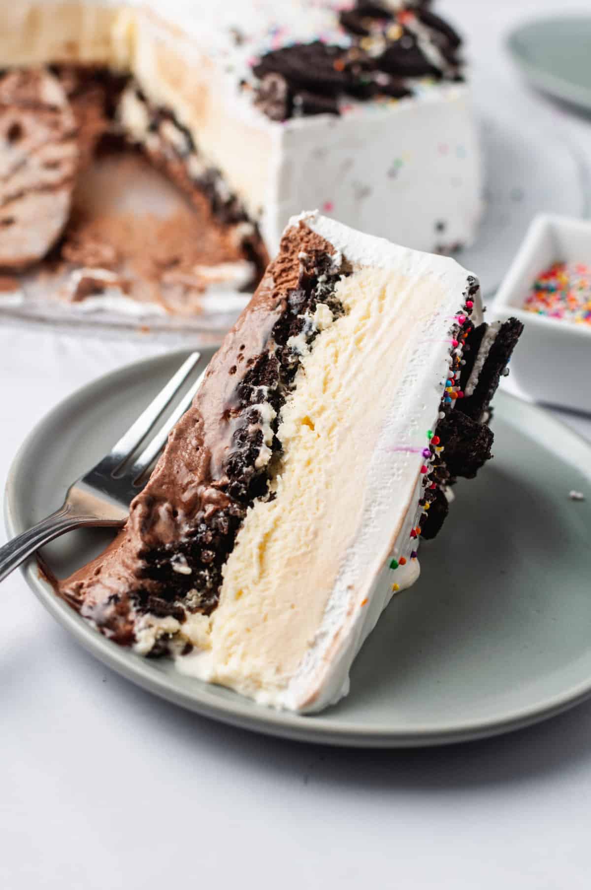 slice of Copycat Dairy Queen Ice Cream Cake on its side served on a grey round plate with a silver fork.