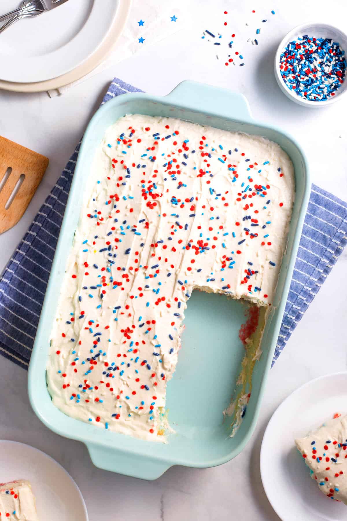 top down view of red white and blue jello poke cake topped with cake frosting and sprinkles