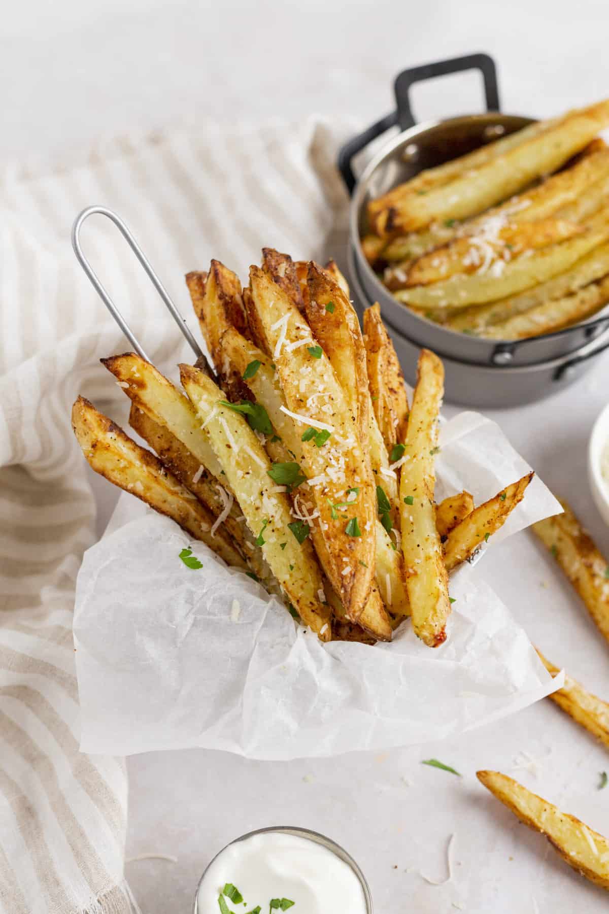air fryer parmesan fries served in a parchment lined metal dish