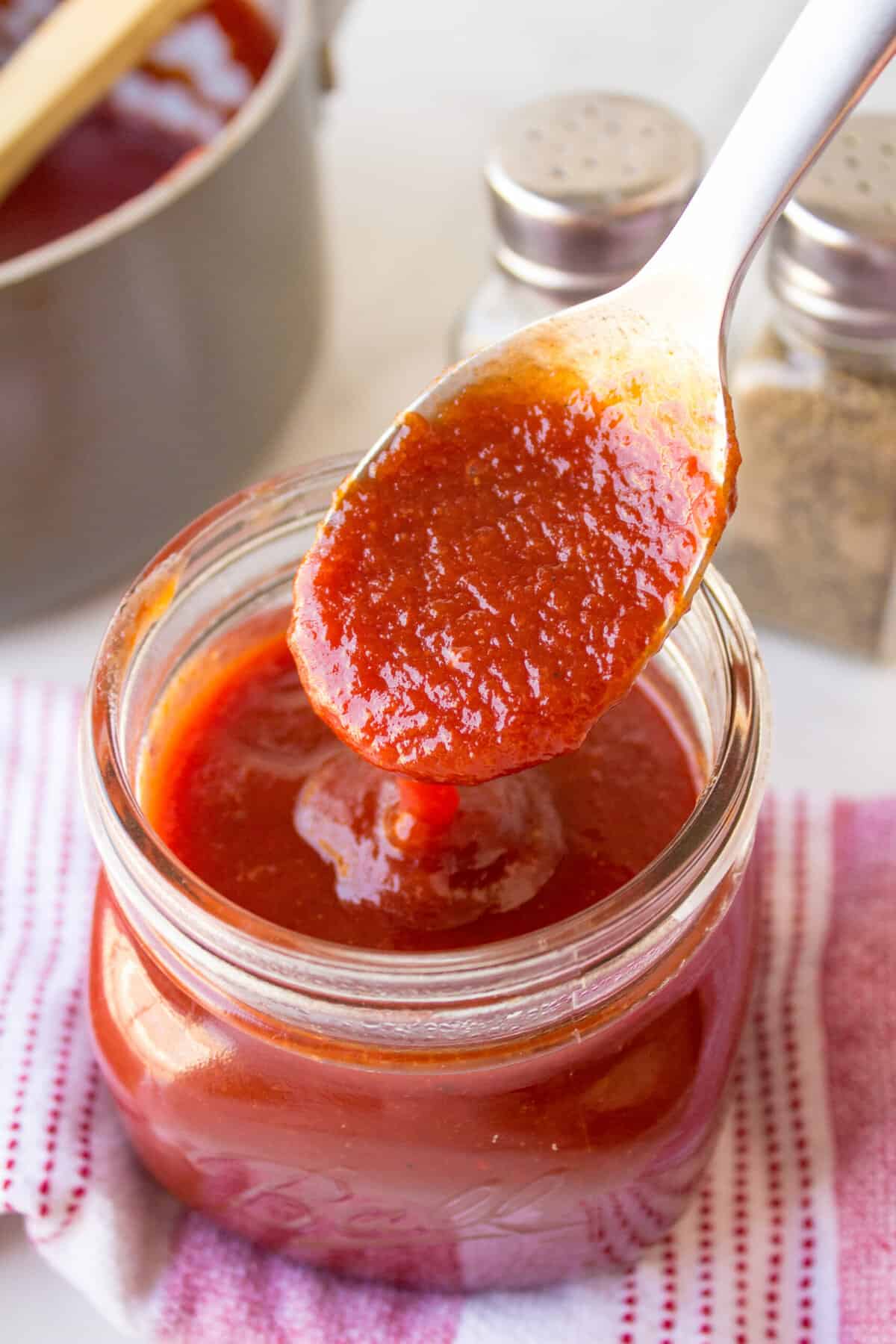 homemade bbq sauce stored in a mason glass jar with a spoonful of bbq sauce