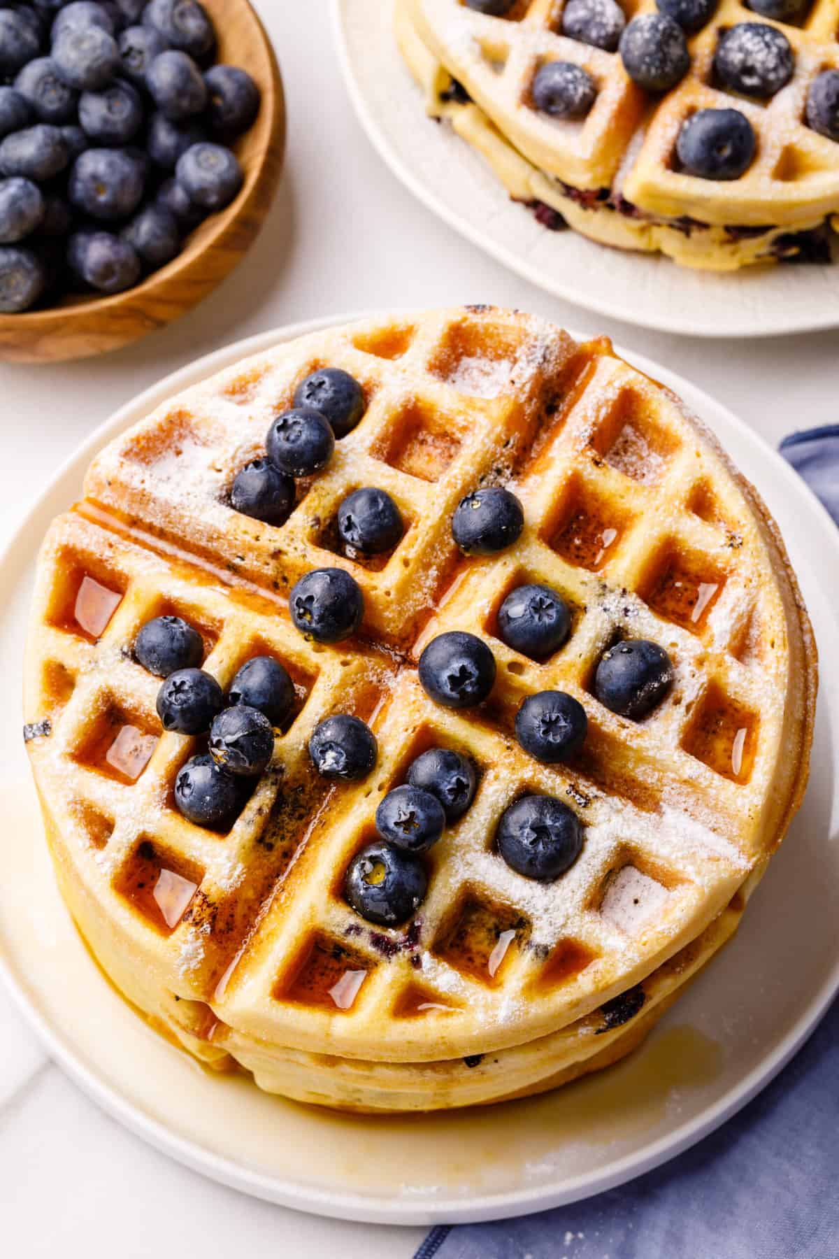 top down view of blueberry waffles with syrup served on a white round plate