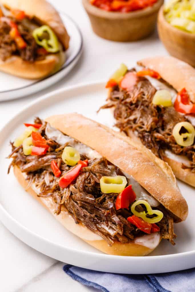 close up image of italian beef sandwiches served on a white round plate