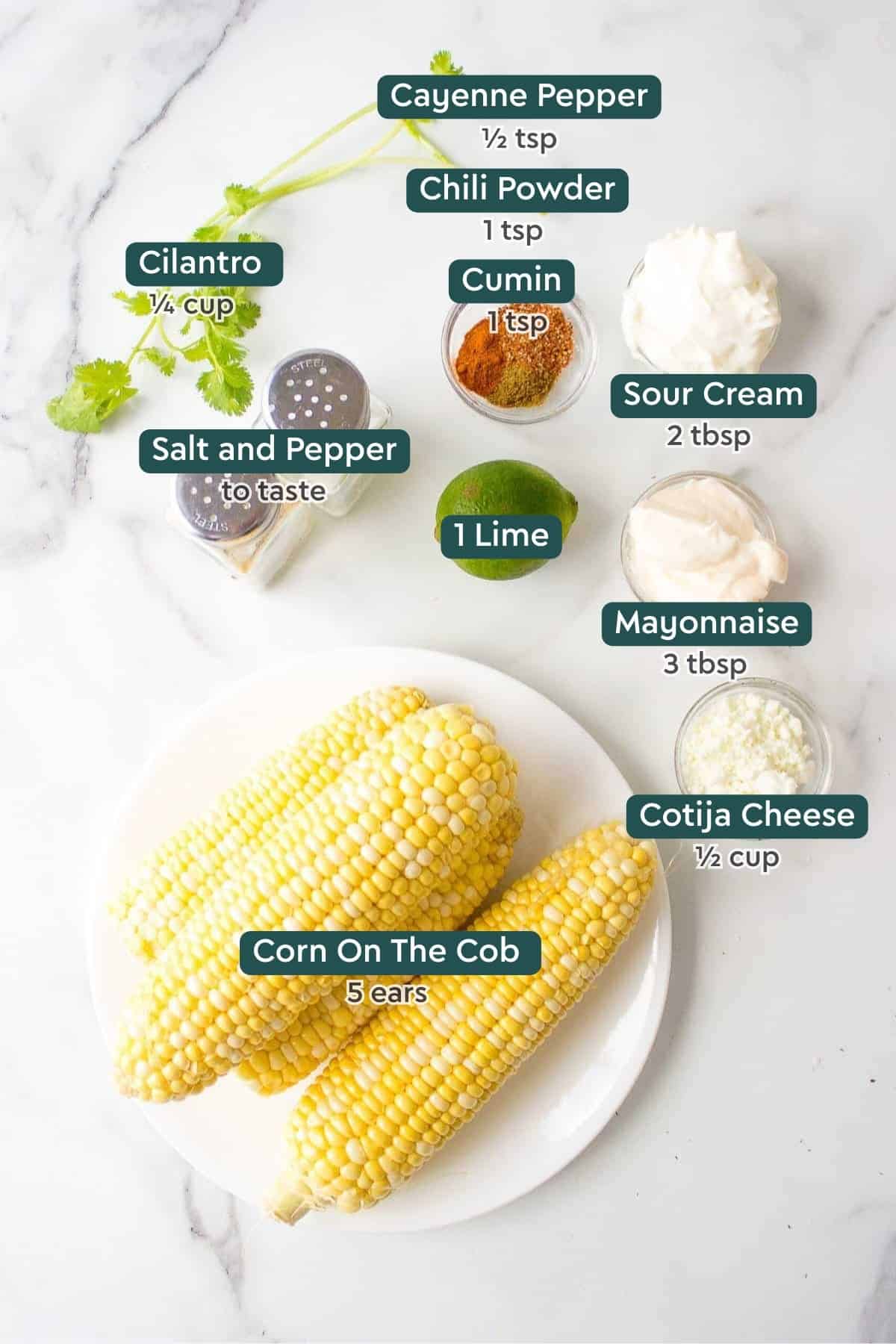 Ingredients for easy Mexican corn, including cayenne, chili powder, cumin, cilantro, salt, pepper, sour cream, lime, mayo, cotija, and corn.