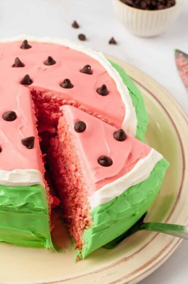 A slice of watermelon cake being lifted from a platter.