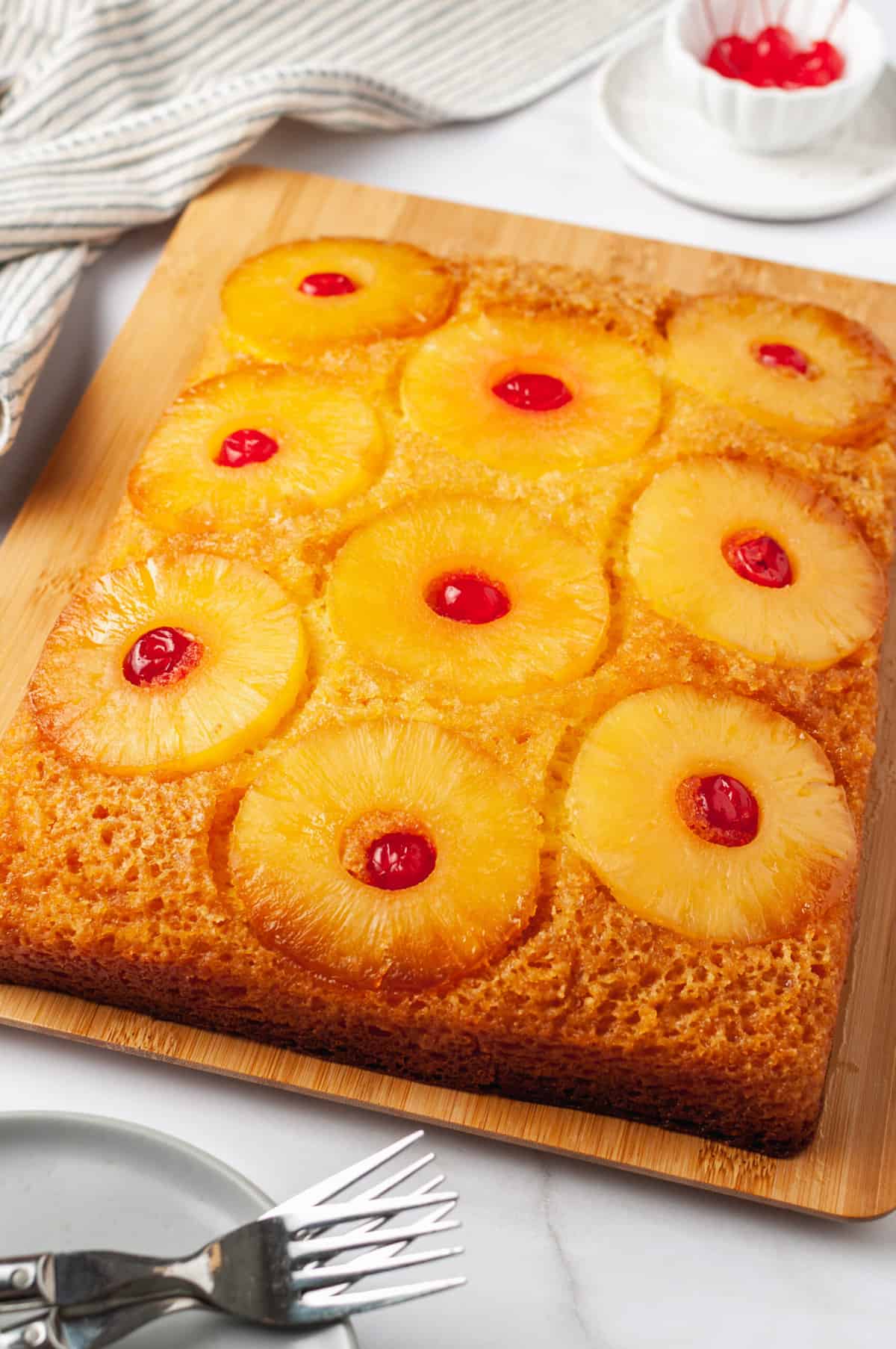 baked pineapple upside down cake sitting on a wooden cutting board