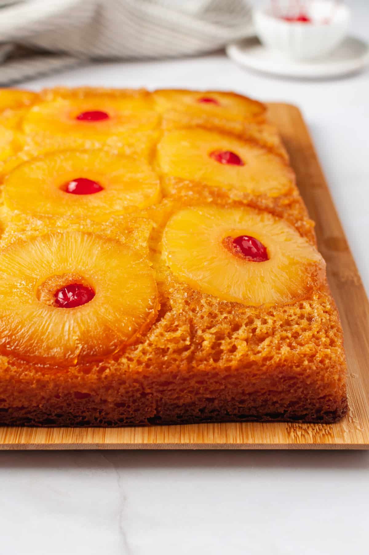 close up image of pineapple upside down cake sitting on a wooden board