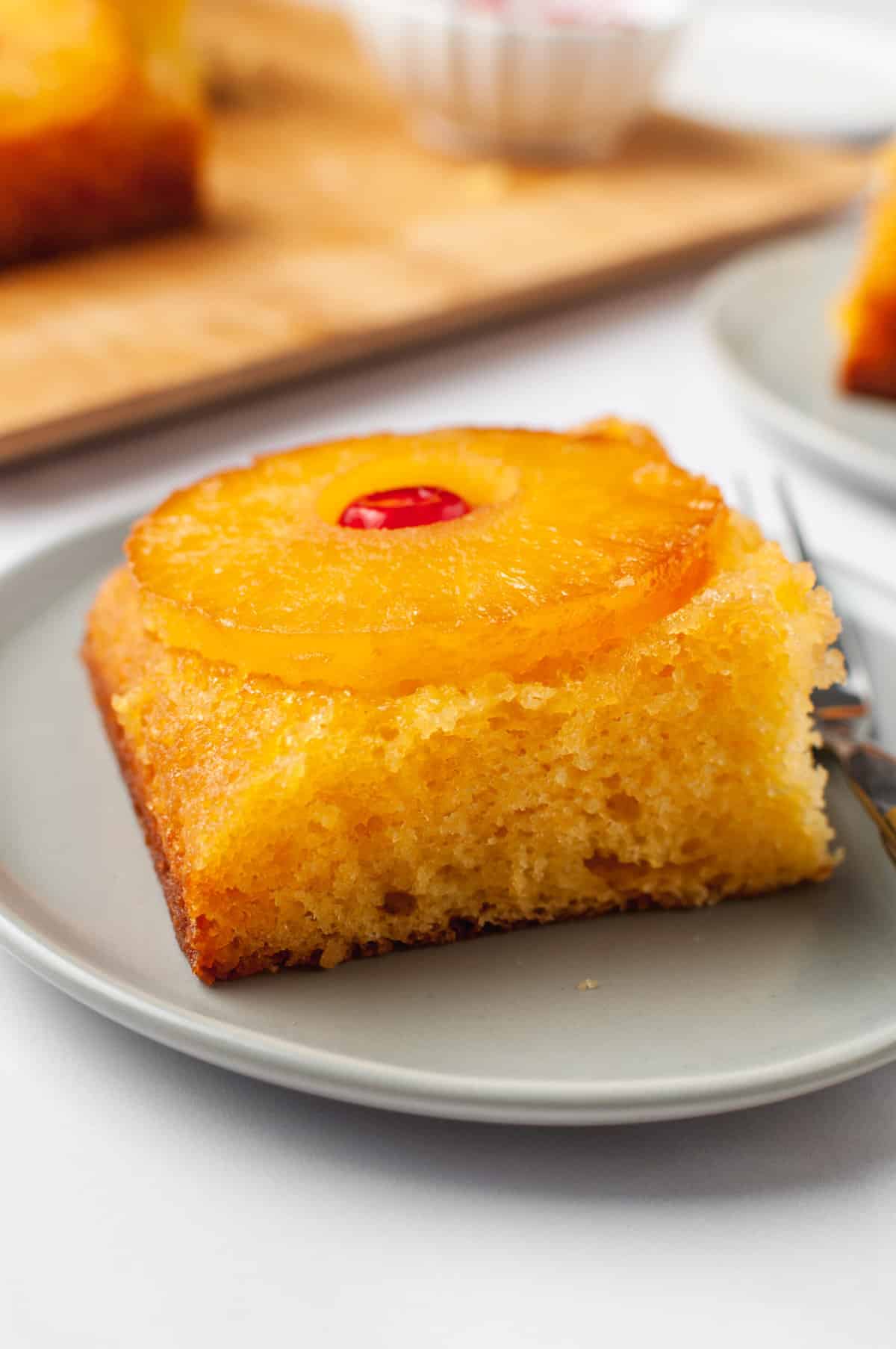 serving of pineapple upside down cake served on a grey plate with a silver fork