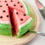 A slice of watermelon cake being lifted from a platter.