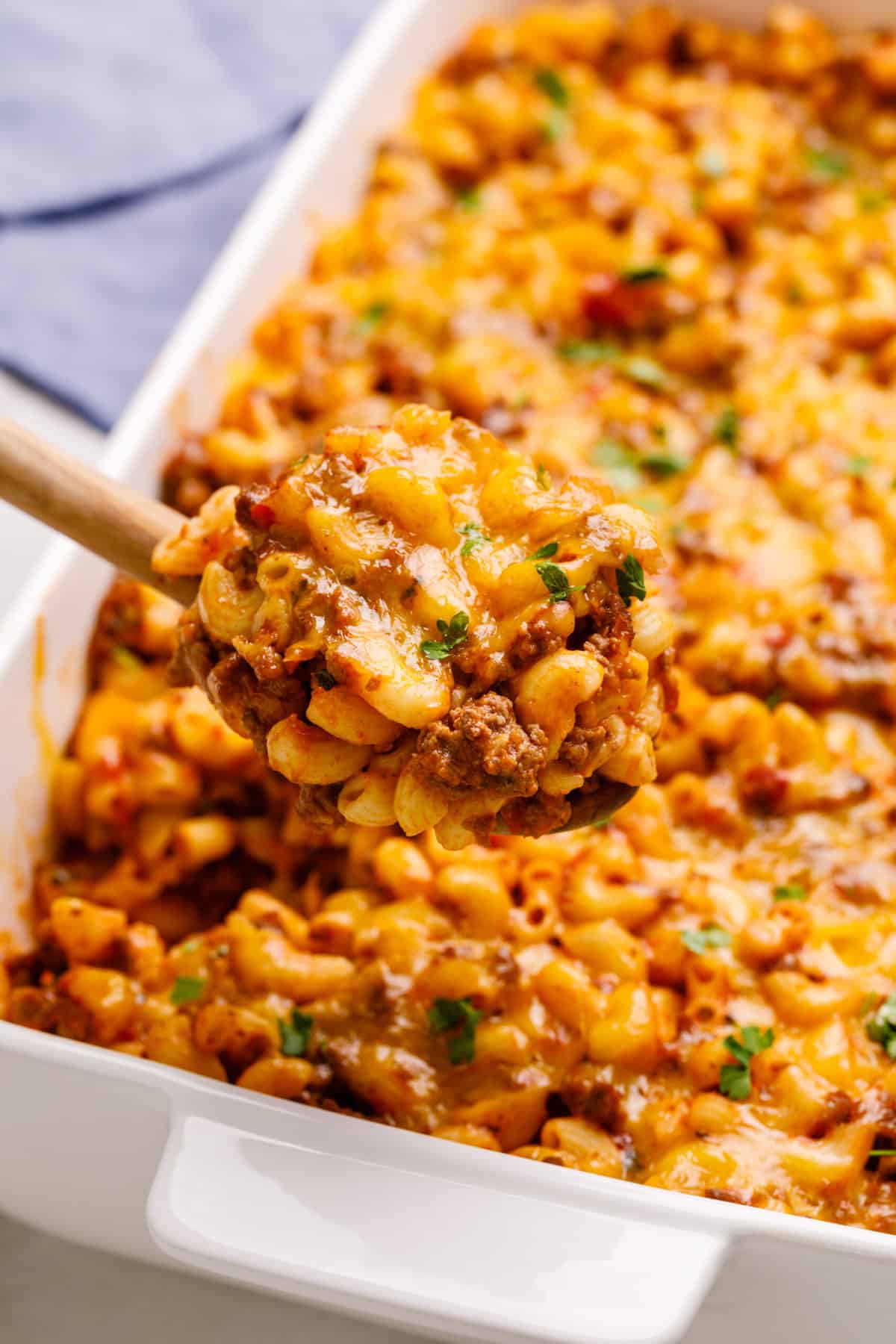 close up image of a wooden spoonful of ground beef casserole