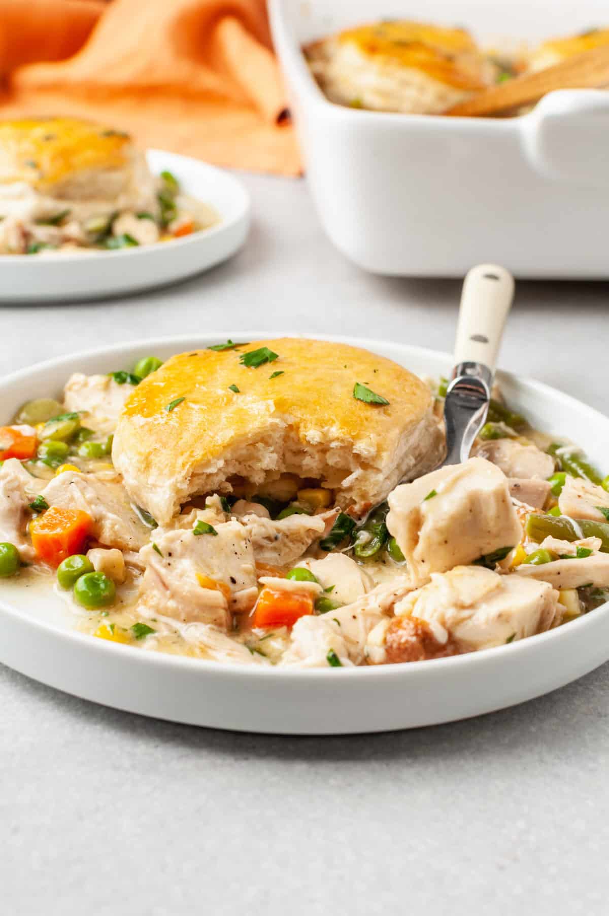 serving of chicken pot pie casserole served on a shallow white plate with a fork