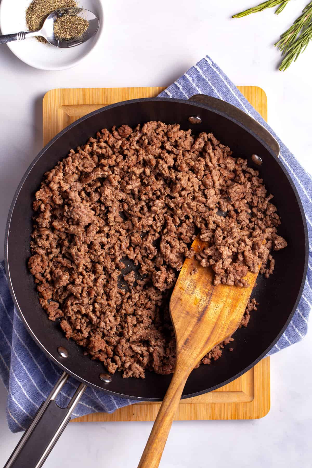 top down image of browned ground beef served in a pan with a wooden spatula.