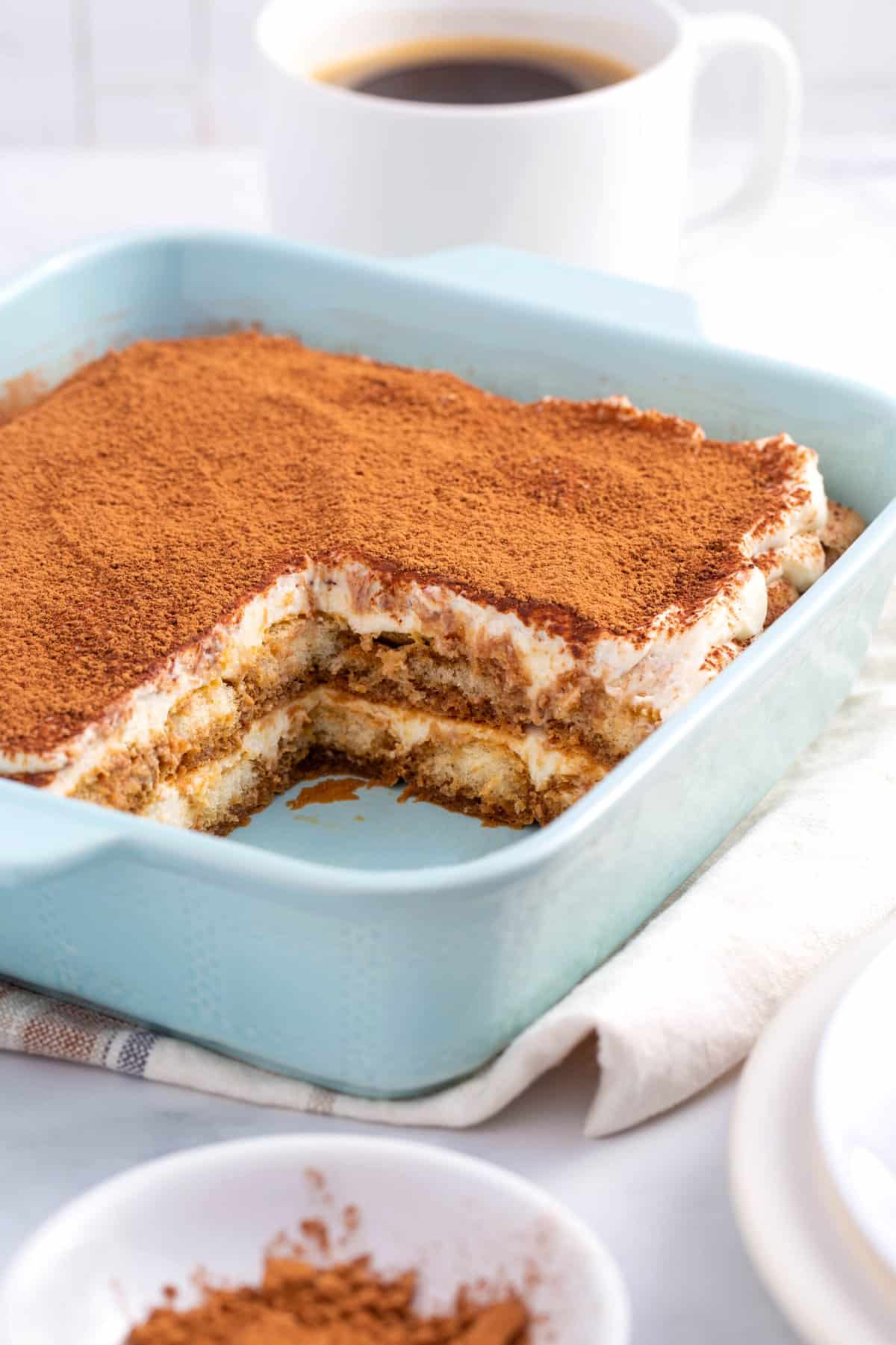 cross section of tiramisu cake served in a light blue caking dish