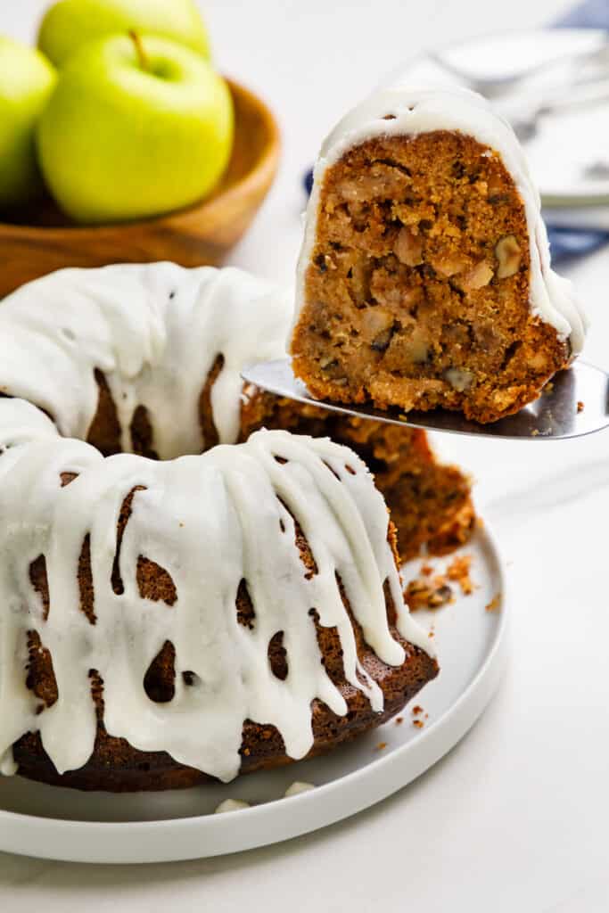 Slice of apple bundt cake being lifted from tray